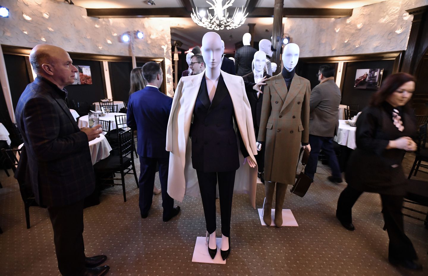 A room full of people with several mannequins wearing clothing