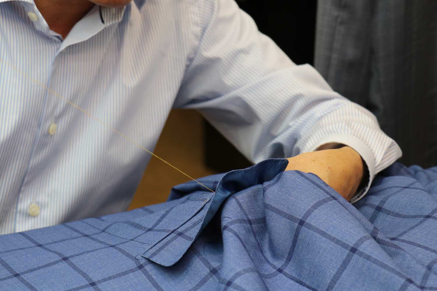 A closeup of cloth being sewed by Mr. Sid Makes House Calls. Introducing Monogram.