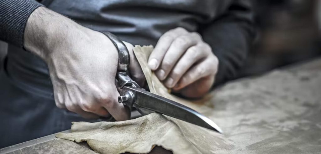 Photo of leather being cut with scissors by Hestra